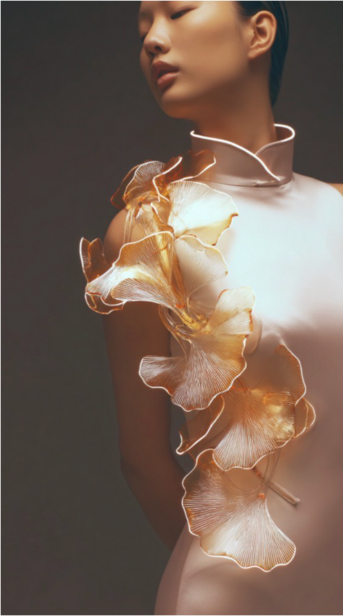 Close view of illuminated sculptural floral forms unfolding across a qipao